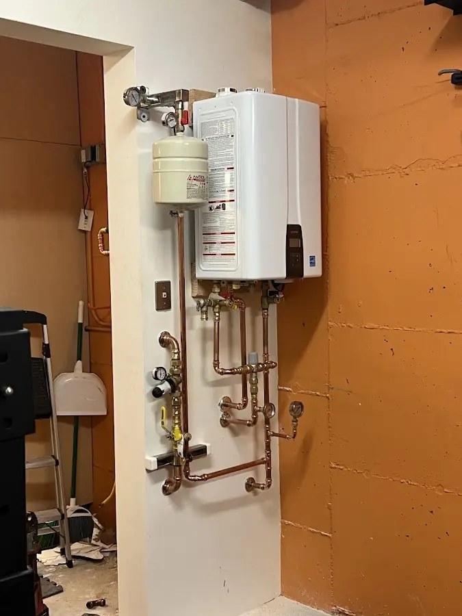 Plumbing technician inspecting water heater connections in Manchester